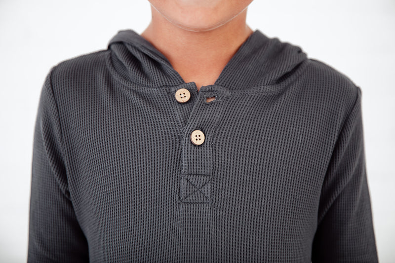Close-up of button detail on a grey boys shirt. 