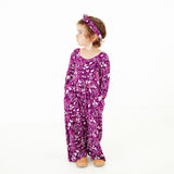Girl with hands in pockets of romper.