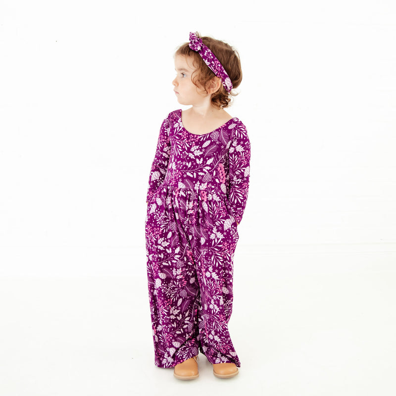 Girl with hands in pockets of romper.