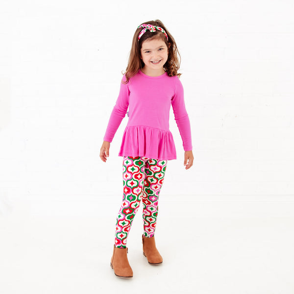 Girl wearing a pink top and retro holiday print leggings.