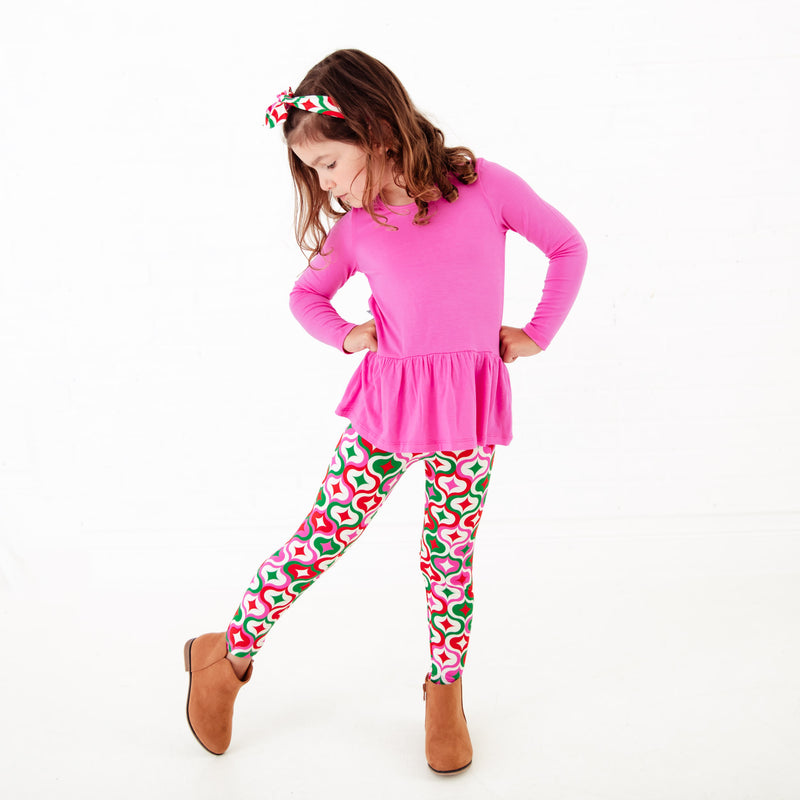 Girl wearing a pink top and colorful leggings.