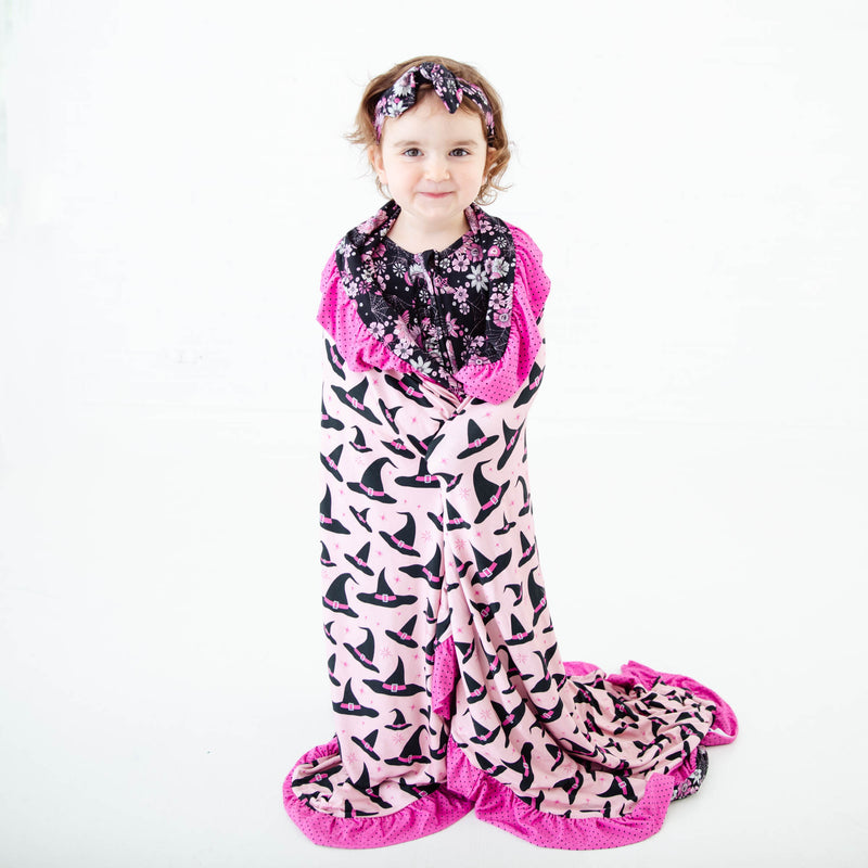 Toddler wrapped in pink witches hat blanket.