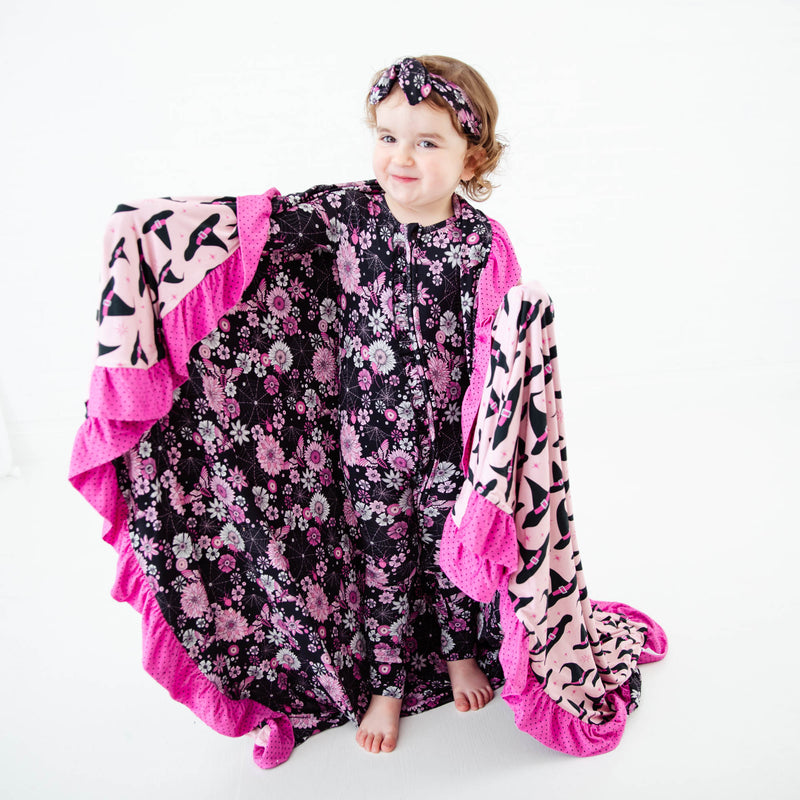 Toddler showing floral side of reversible blanket.