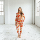 Woman wearing a colorful onesie in a bright, white room.