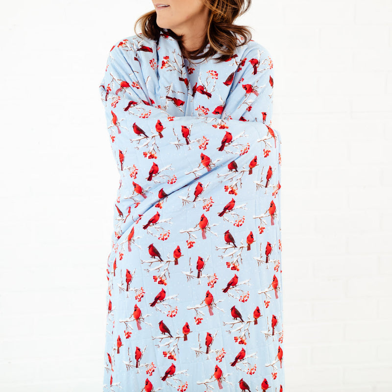 Woman wrapped up in a blue blanket with cardinals. 