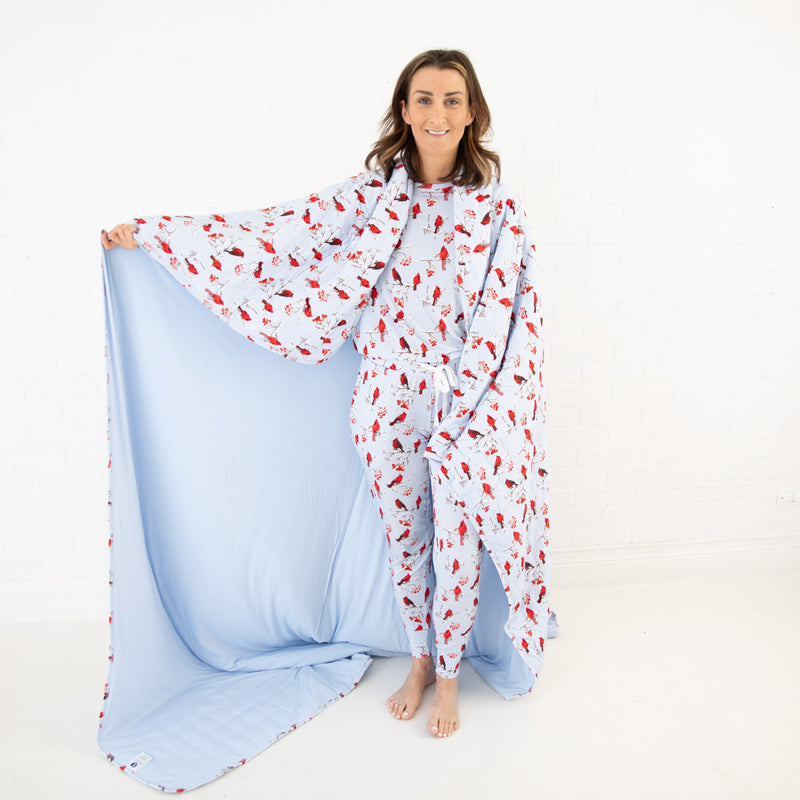 Woman showing a blue blanket with cardinals.