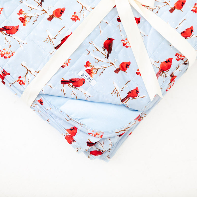 Folded blanket with red cardinal print.