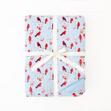 Folded bamboo blanket with cardinal pattern on a light blue background.