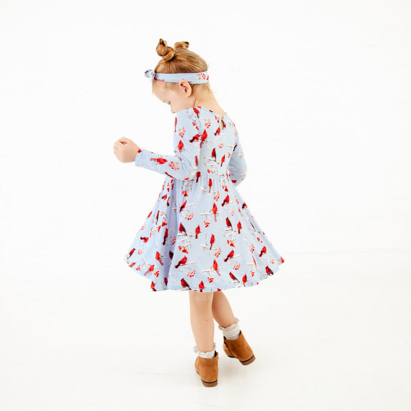 Child twirling in a cardinal print dress.