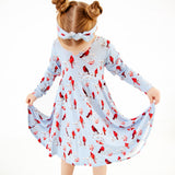 Child wearing a dress with winter cardinal print. 