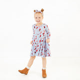 Young girl wearing a dress with a cardinal pattern.