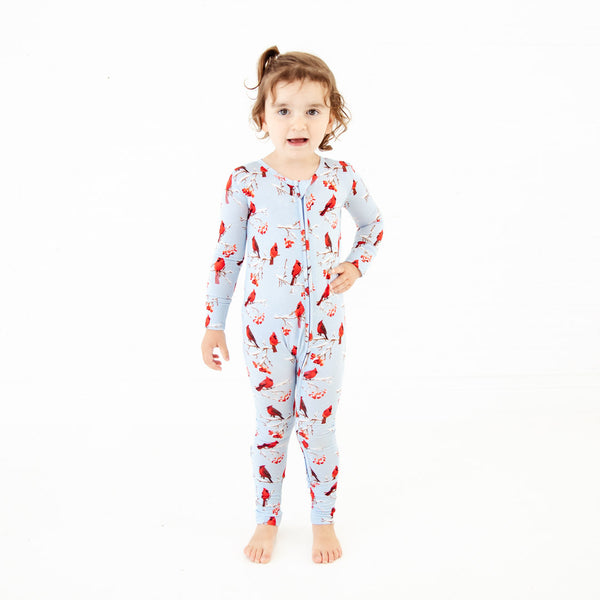 Child wearing cardinal print footed pajamas.