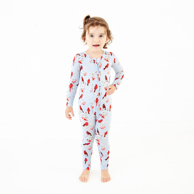 Child wearing cardinal print footed pajamas.