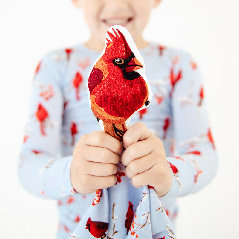 Child holding an embroidered cardinal on a child's lovey. 