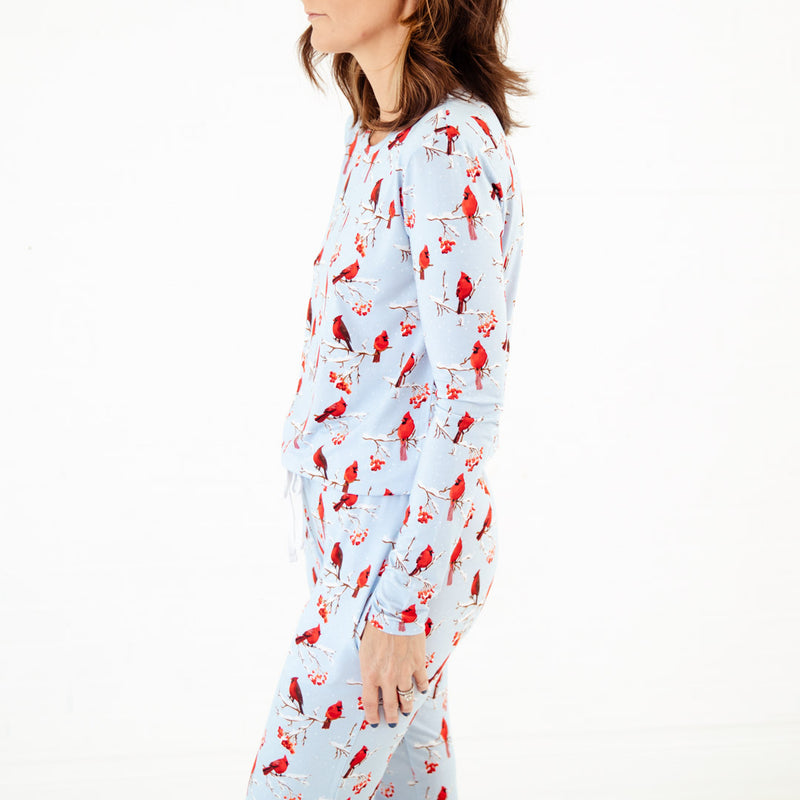 Woman wearing a long-sleeve pajama top with cardinal bird pattern.