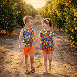 Two children holding hands in an orange grove at sunset.