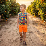 Child walking through an orange grove with a colorful shirt and orange shorts at sunset.