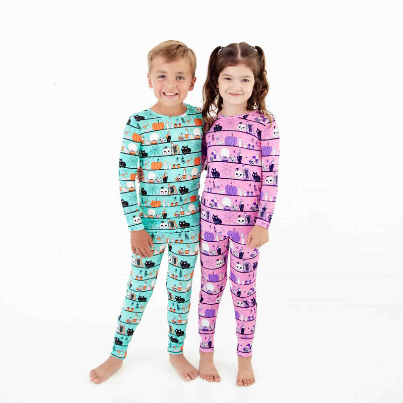 Two children wearing coordinating halloween pajamas. 