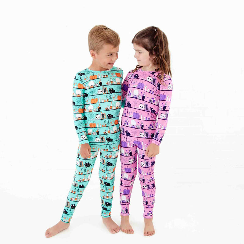 Two children wearing coordinating halloween pajamas. 
