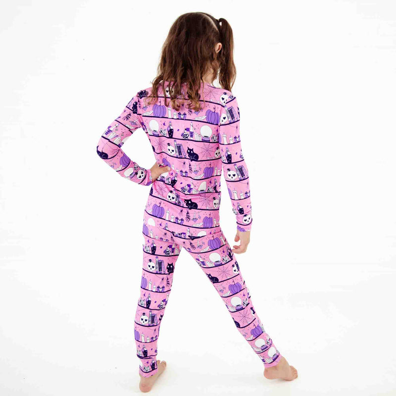 Child wearing pink halloween themed pajamas. 