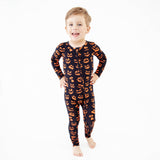Boy in black and orange pumpkin pajamas. 