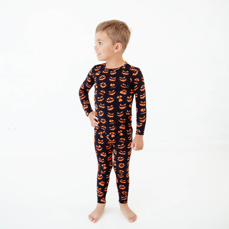 Child wearing black and orange jack-o-lantern pajamas. 