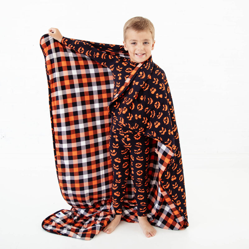 Child holding a halloween themed blanket. 