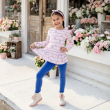 Young girl in a pink outfit standing in front of 'The Pink Petal' store with floral displays.