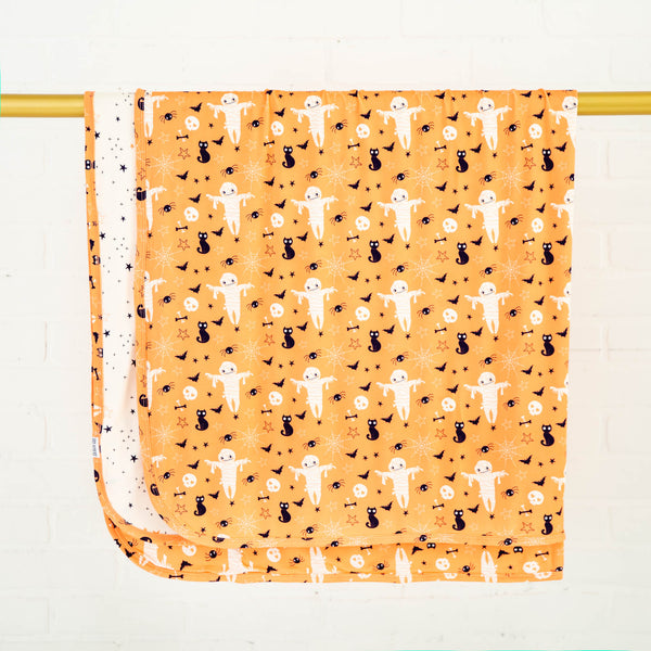 Orange Halloween themed bamboo blanket on rack. 