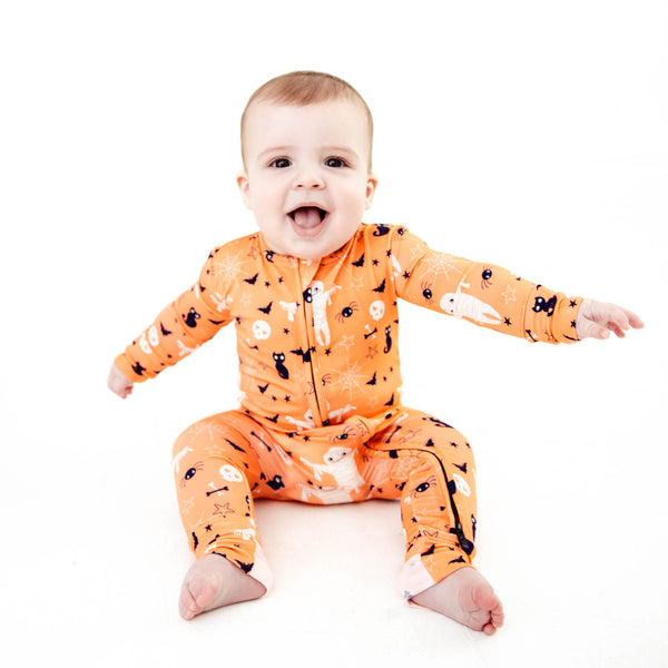 Baby wearing orange halloween themed bamboo pajamas.
