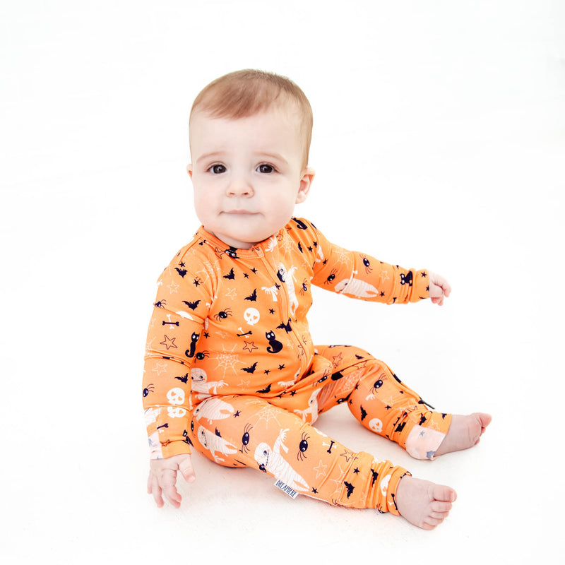 Sitting baby in halloween pajamas with mummys.