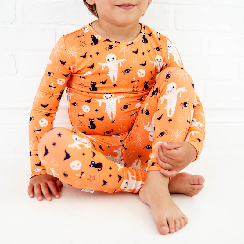 Child sitting in halloween themed pajamas.
