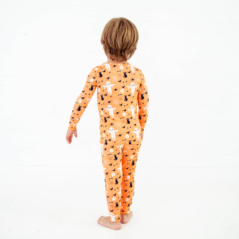 Toddler wearing orange halloween themed pajamas.