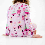 Child sitting in purple nutcracker print pajamas. 