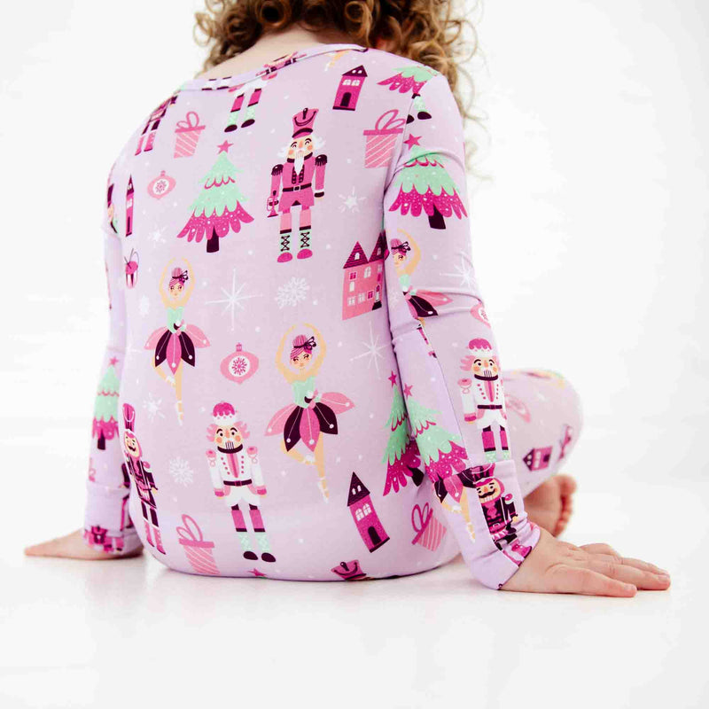 Child sitting in purple nutcracker print pajamas. 