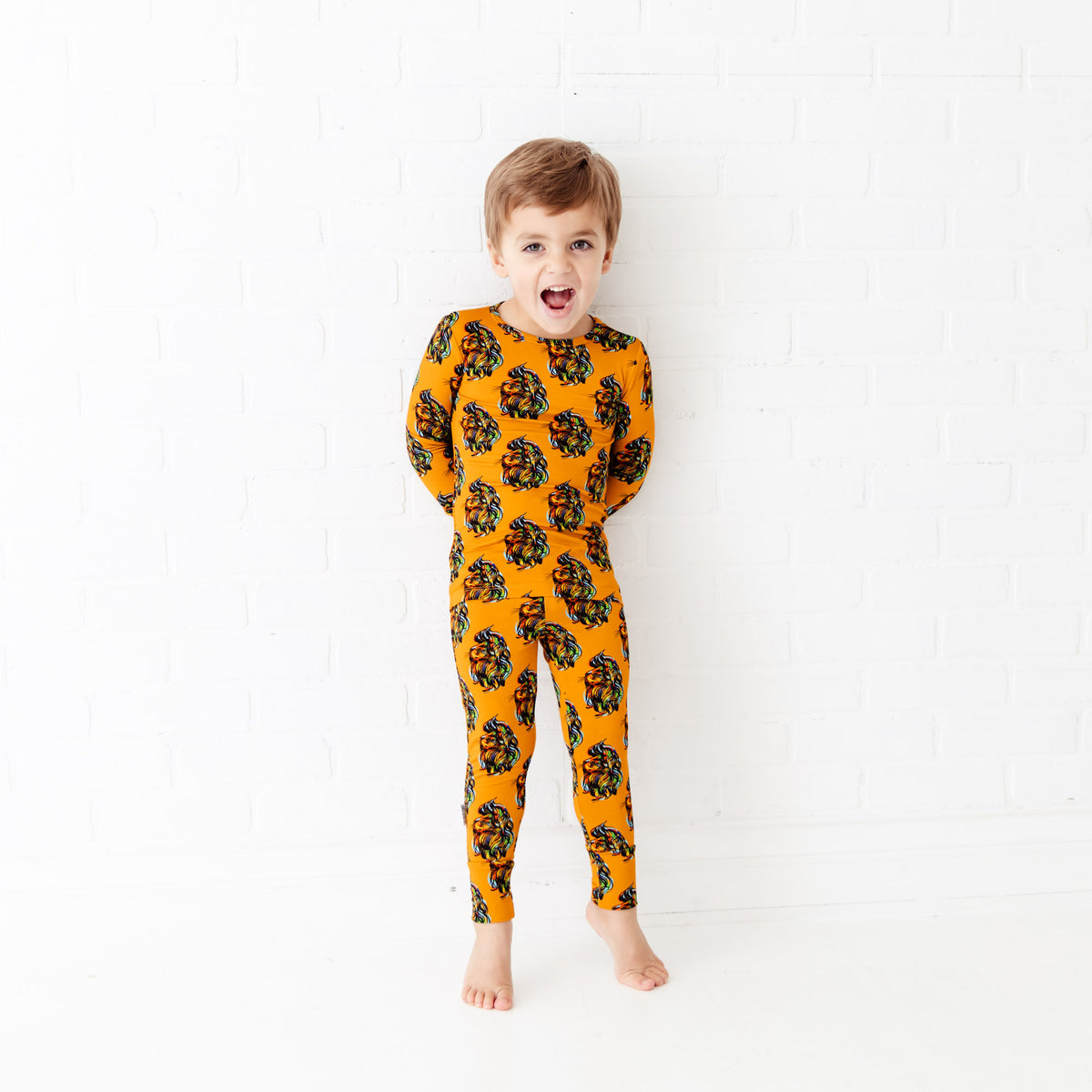 Kids’ two-piece pajamas with bold orange lion print from Dreamiere