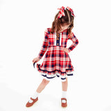 Girl wearing red plaid dress and bows. 