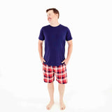 Man wearing a shirt and red plaid shorts.