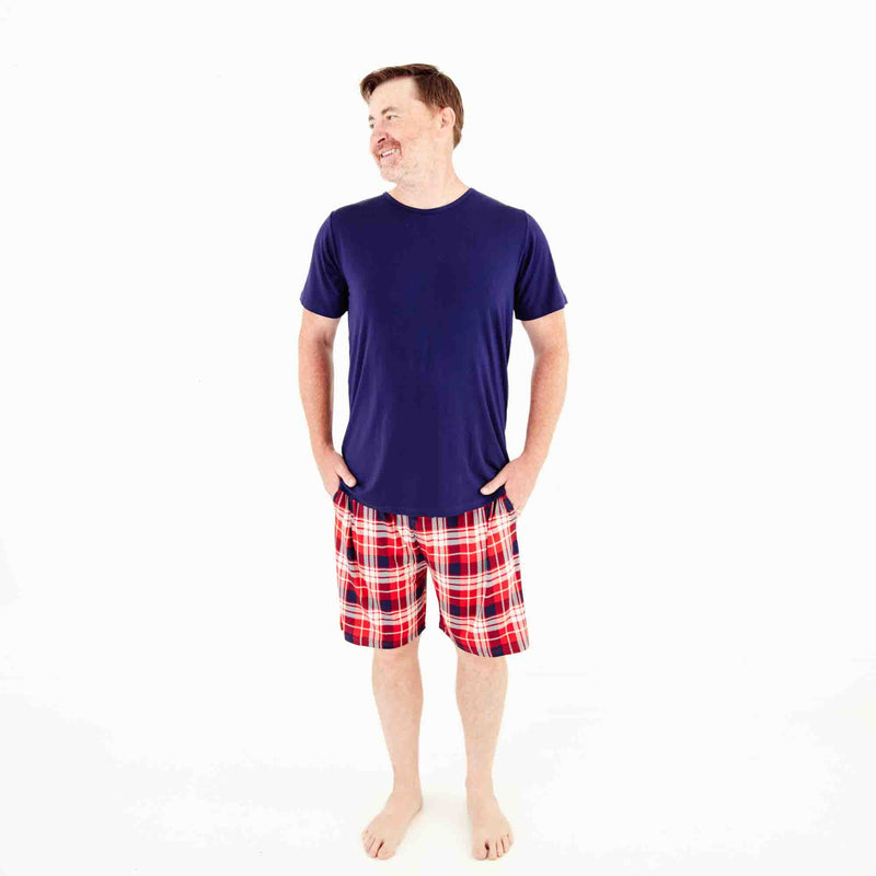 Man wearing a shirt and red plaid shorts.