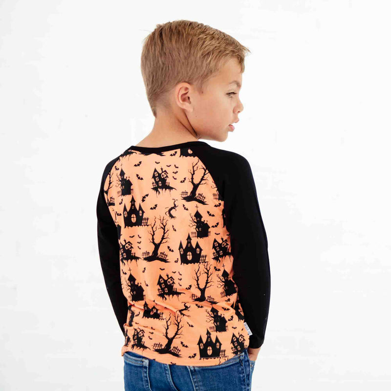 Child wearing an orange and black Halloween themed shirt. 