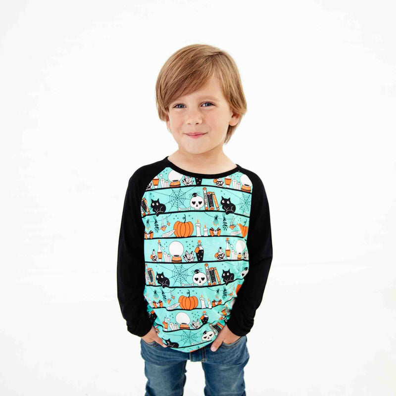 Child wearing a teal Halloween-themed shirt.