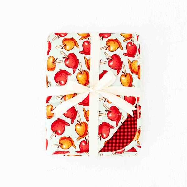 Folded quilted blanket with caramel apple print. 
