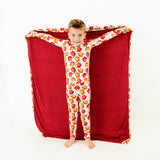 Child holding a blanket matching their fall pajamas. 