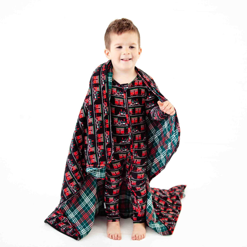 Child wrapped in holiday print blanket. 
