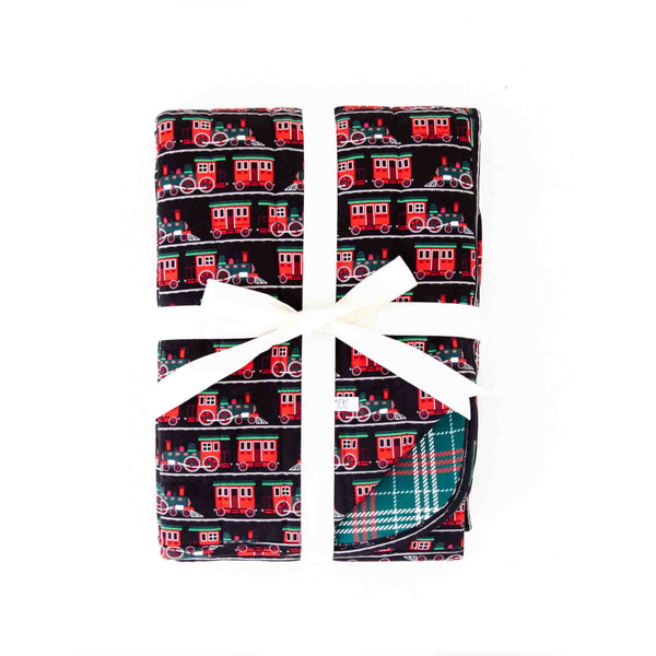 Folded Holiday Blanket with trains and plaid. 