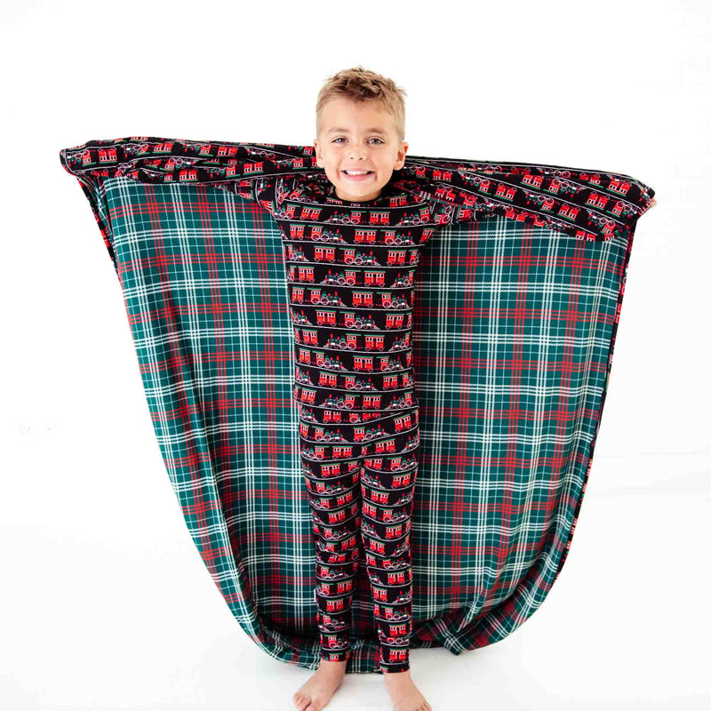 Boy wearing pajamas and holding a matching blanket. 