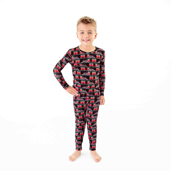 Boy wearing holiday train print pjs. 