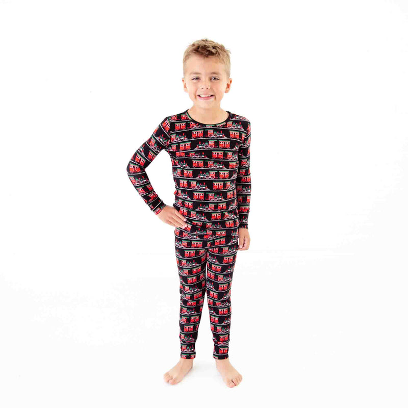 Boy wearing holiday train print pjs. 